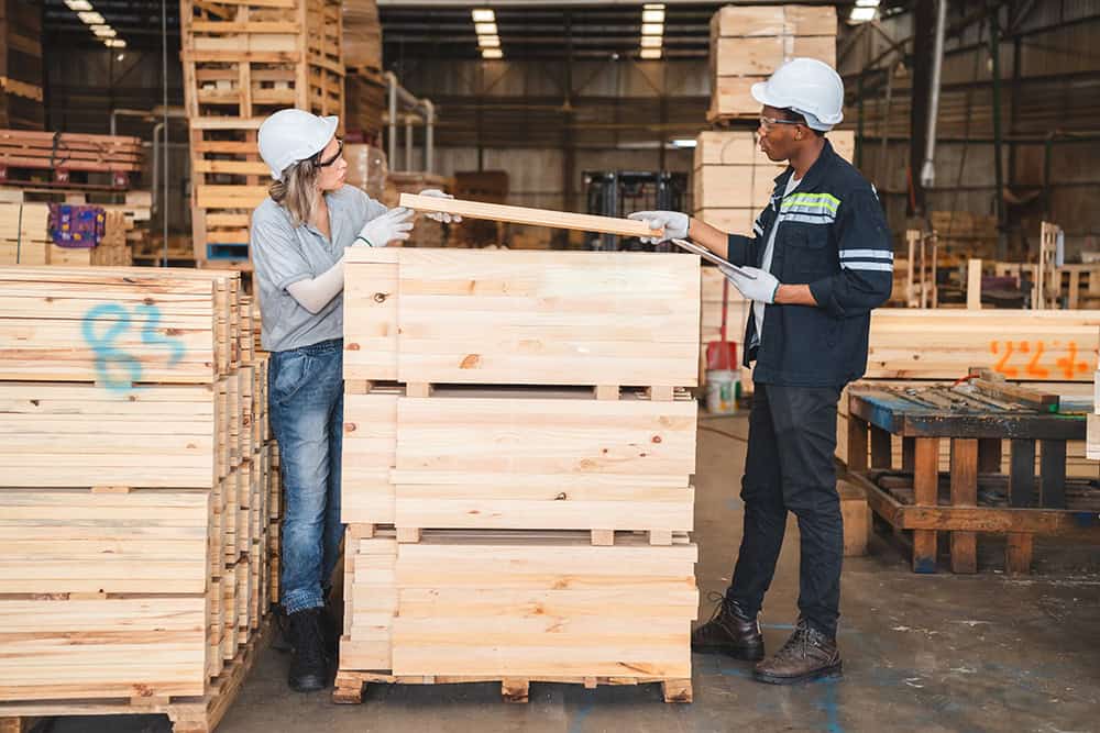 Two people working in a warehouse with wooden pallets. | Unlimited Solutions