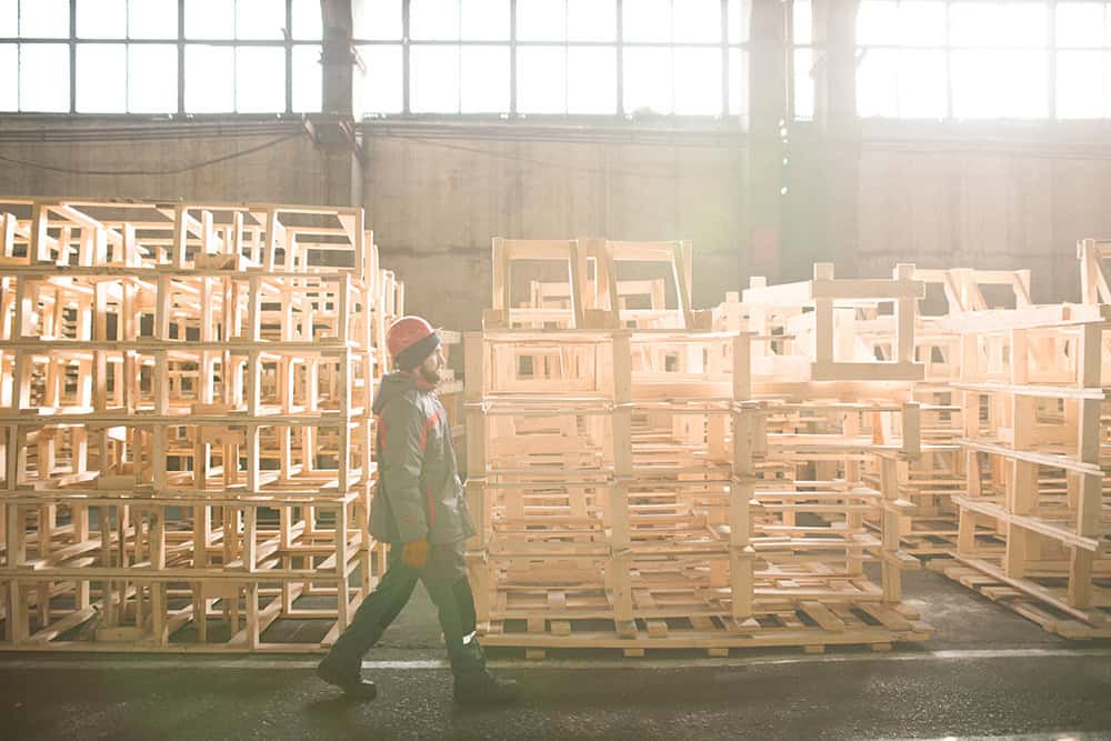 A person walking through a warehouse full of wooden pallets. | Unlimited Solutions