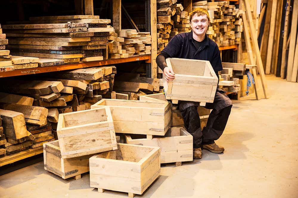 A man sitting on a pile of wooden crates. | Unlimited Solutions
