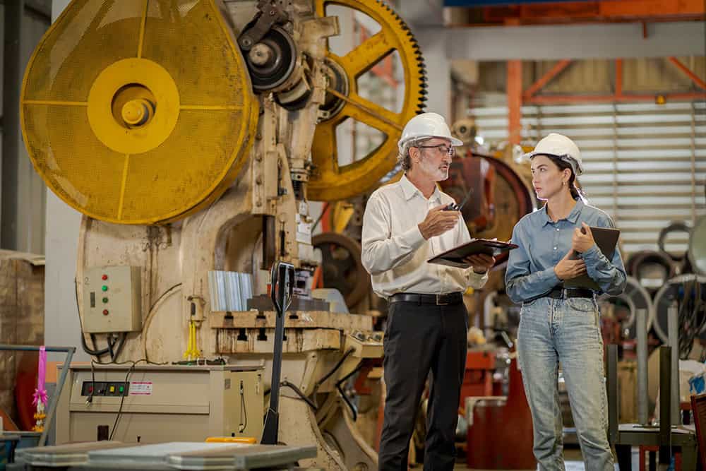 Two people standing in front of a machine. | Unlimited Solutions
