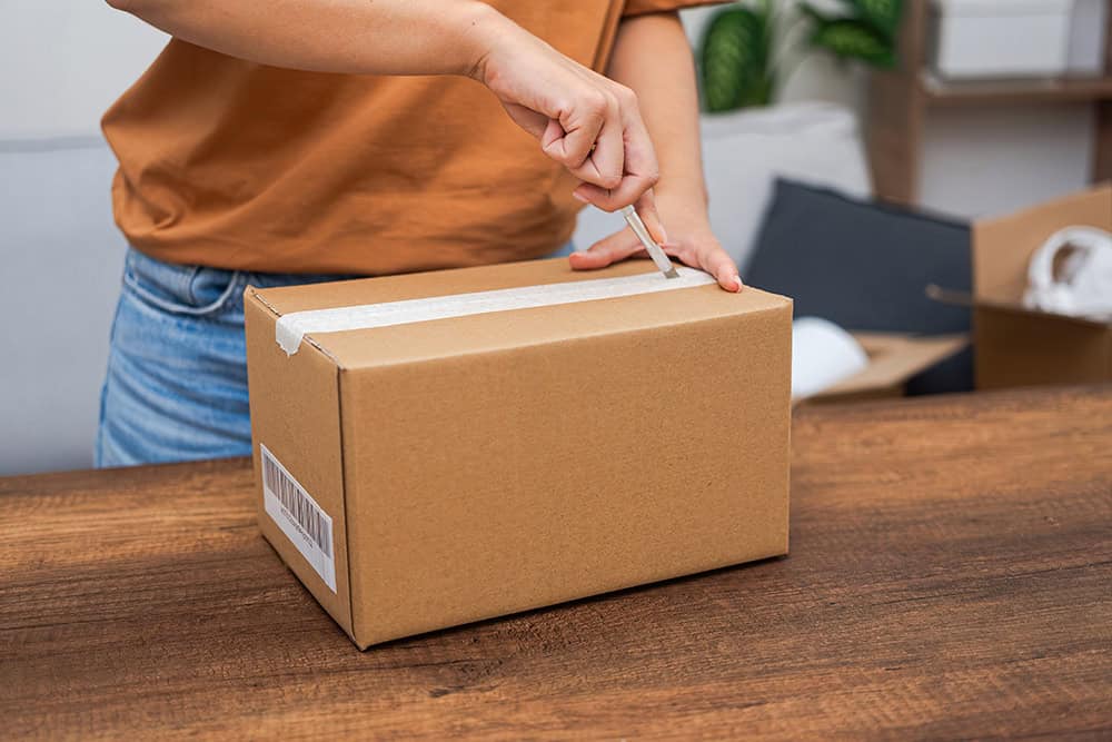A woman is opening a cardboard box. | Unlimited Solutions