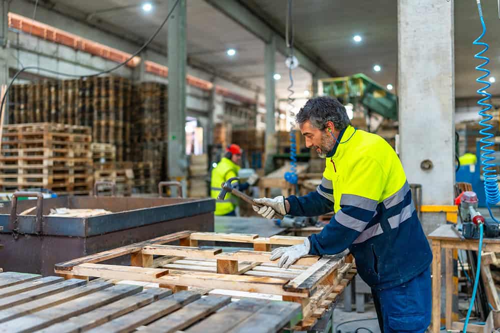 A man working in a factory with wooden pallets. | Unlimited Solutions
