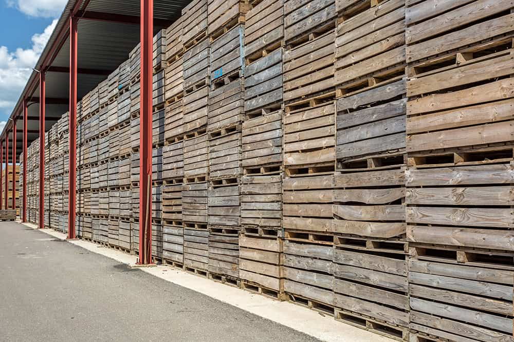 A row of wooden pallets stacked against a wall. | Unlimited Solutions